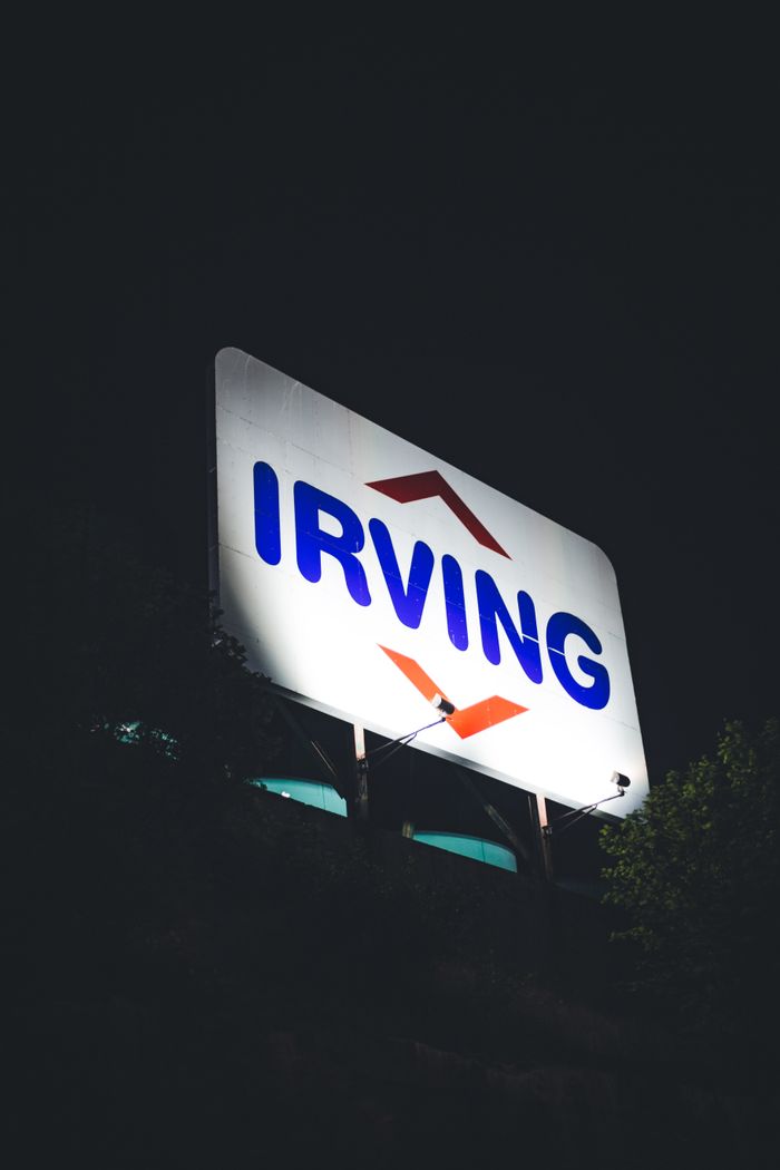 our-story Close-up of a large illuminated Irving sign against a dark night sky.