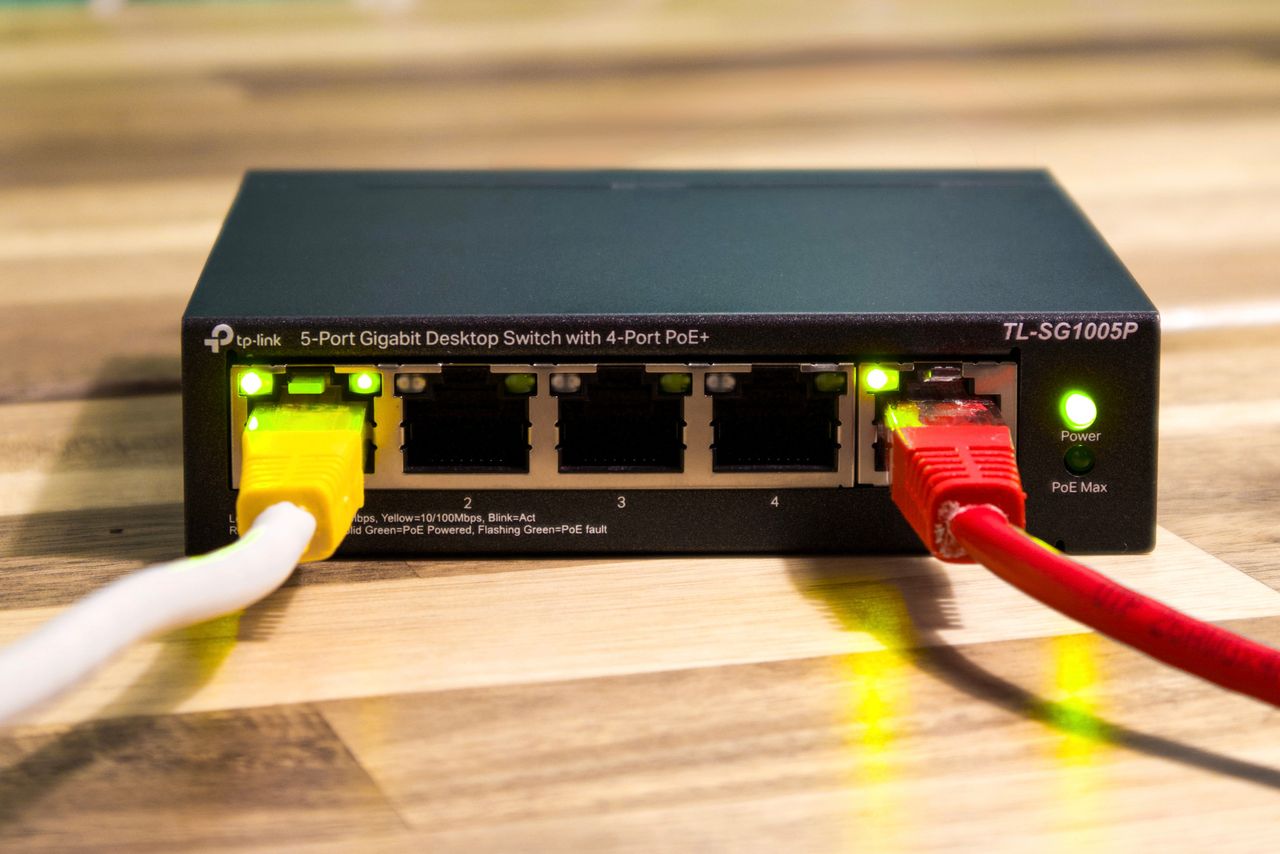 about-us Close-up of a TP-Link Ethernet switch with yellow, red, and white cables connected.