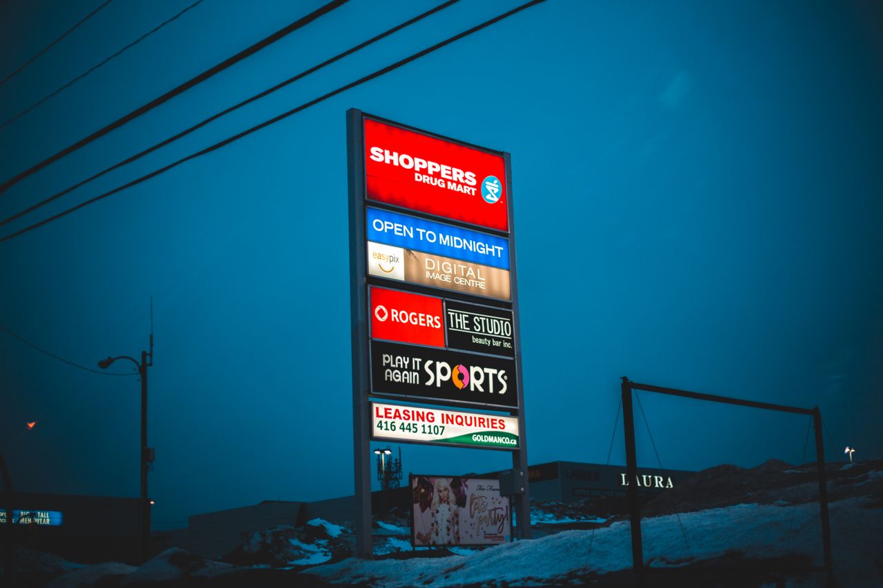 Illuminated big board with signs of shops and stores under dark sky in winter season